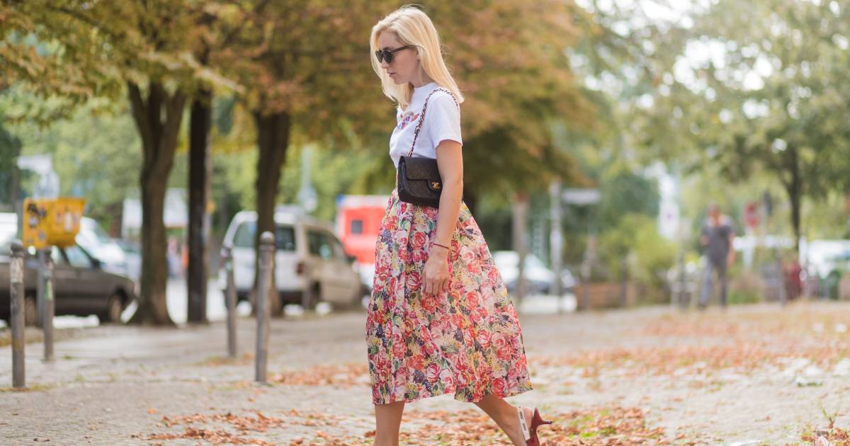 Sonia Lyson wearing a midi skirt with floral print Ganni, a white T-shirt with the print Love Dog from Ganni, a black Chanel vintage bag, vintage sunglasses, red Dior shoes on August 28, 2017 in Berlin, Germany.