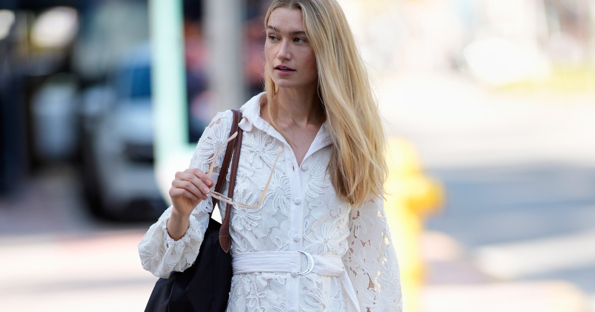MIAMI, FLORIDA - OCTOBER 23: Maggie Krebs is seen wearing straight blonde hair, oversized light pink sunglasses, a Garota white lace long-sleeve belted mini dress, carrying a large black shoulder bag, and Dolce Vita beige knee-high boots outside Naeem Khan, during Miami Fashion Week on October 23, 2025 in Miami, Florida. (Photo by 305pics/Getty Images)