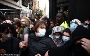 Protesters wearing keffiyehs link arms to try to block people from attending Tommy Robinson’s visit to Oxford Union – as pubs board windows and close early amid warnings of ‘unrest’