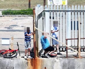 The battle for a French-owned beach…in Sussex: Moment teenagers scale fence to cool off in the sea – after firm stopped locals using it for 18 years