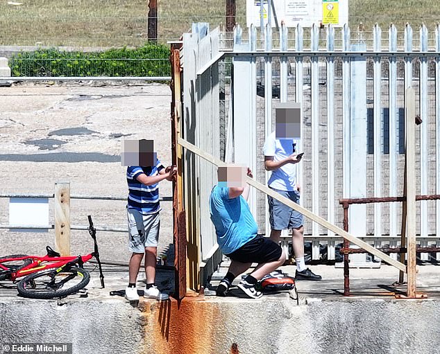 The battle for a French-owned beach…in Sussex: Moment teenagers scale fence to cool off in the sea – after firm stopped locals using it for 18 years