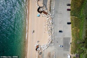 The village that could be lost to the sea forever: Homes almost cut off from civilisation after a winter storm could now be washed away unless £20m defences are urgently built